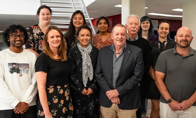 11 scientists standing on stairs looking at camera