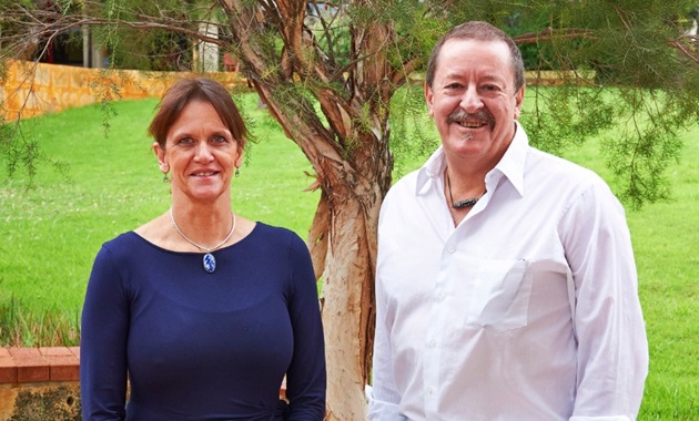 Professor Sue Fletcher and Professor Steve Wilton under a tree smiling at camera