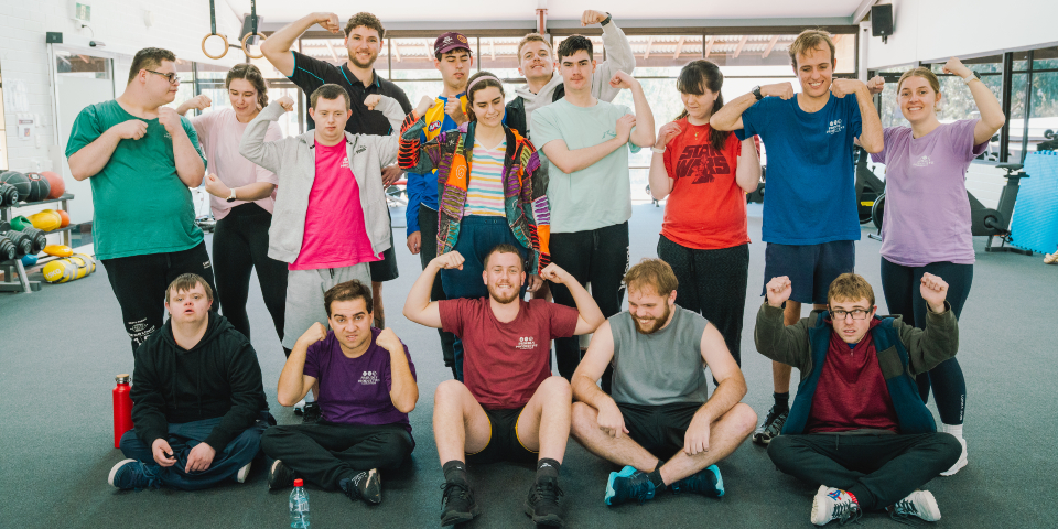 Group of young adults flexing their muscles in the gym