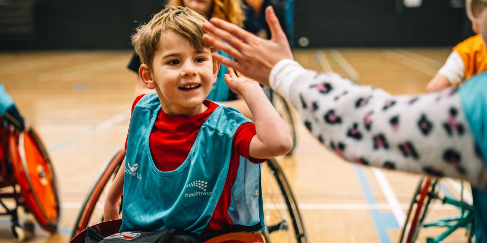 Young boy in wheelchair gives high five