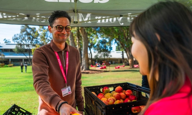 Murdoch International Student Association (MISA) President Saieesivasoriaa Sivagurunathan hands a student an orange