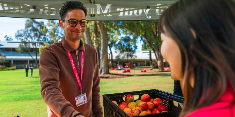 Murdoch International Student Association (MISA) President Saieesivasoriaa Sivagurunathan hands a student an orange