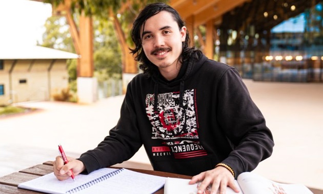 Shaun Pereyra sitting in front of Boola Katitjin at Murdoch University.
