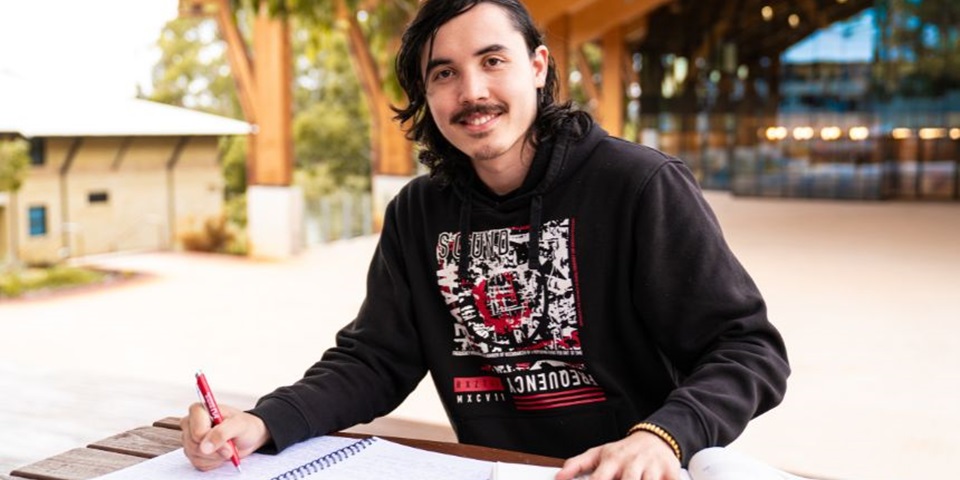 Shaun Pereyra sitting in front of Boola Katitjin at Murdoch University.