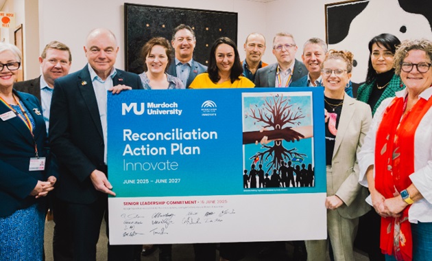 Murdoch University's Senior Leadership Team holding a signed copy of the new Innovate RAP