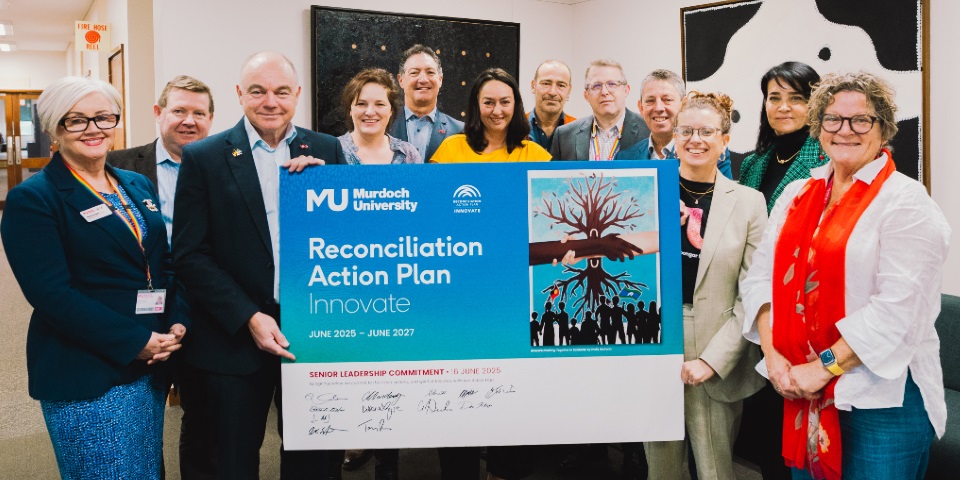 Murdoch University's Senior Leadership Team holding a signed copy of the new Innovate RAP
