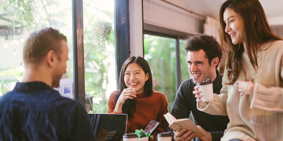 Group of students sitting around table with laptop, notebook and coffee