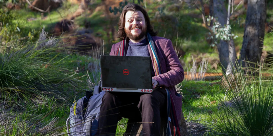 Stephen B Platt sitting amid greenery with a laptop on his lap.