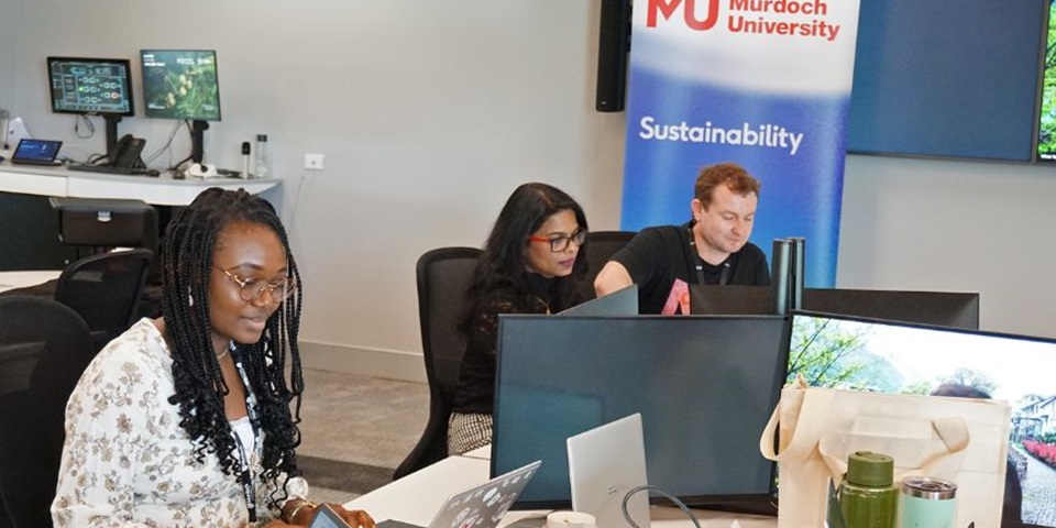 Three students sit around a desk together.