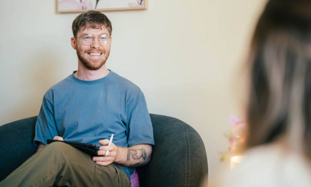 Psychology setting with a psychologist and patient chatting on couches