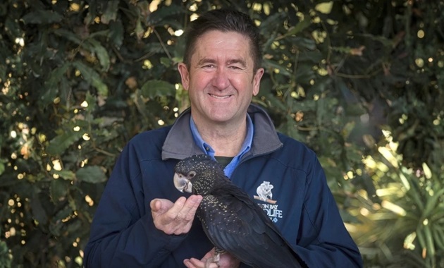 Stephen Van Mil holding a black cockatoo