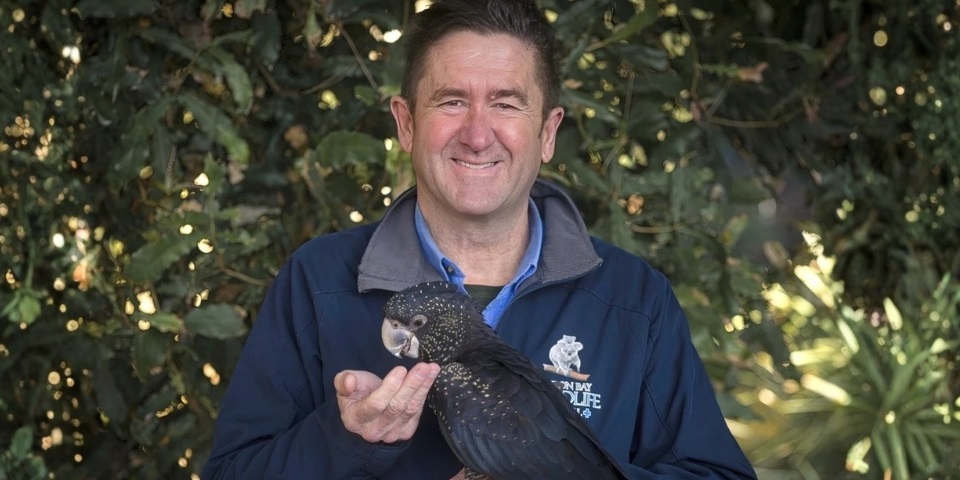 Stephen Van Mil holding a black cockatoo