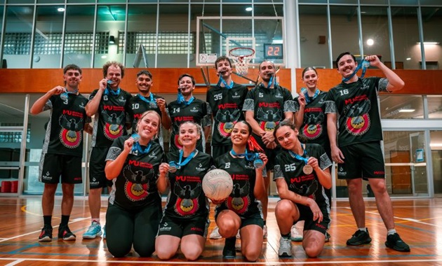Kulbardi's netball team holding their medals and posing on the court in a group.