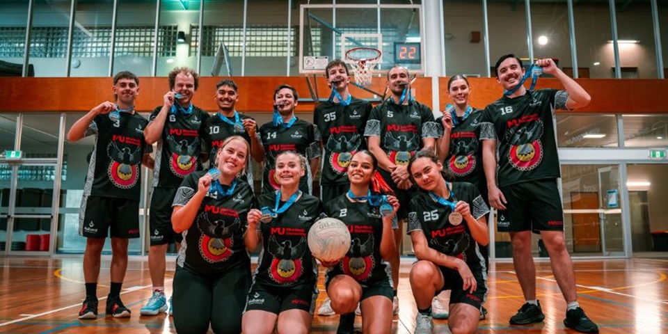 Kulbardi's netball team holding their medals and posing on the court in a group.