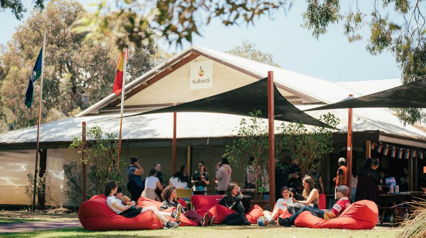 A picture of the front of Kulbardi Aboriginal Centre and a group of people sitting outside on red beanbags.