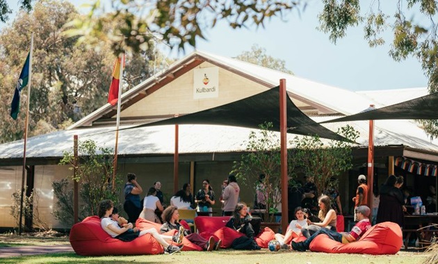 A picture of the front of Kulbardi Aboriginal Centre and a group of people sitting outside on red beanbags.