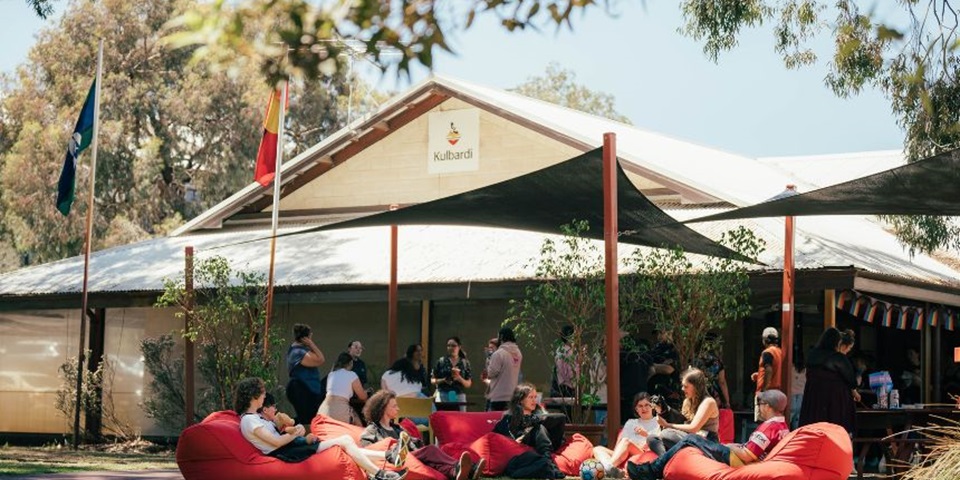 A picture of the front of Kulbardi Aboriginal Centre and a group of people sitting outside on red beanbags.
