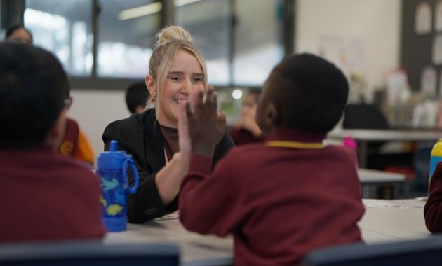 A teacher high-fiving a student, smiling.