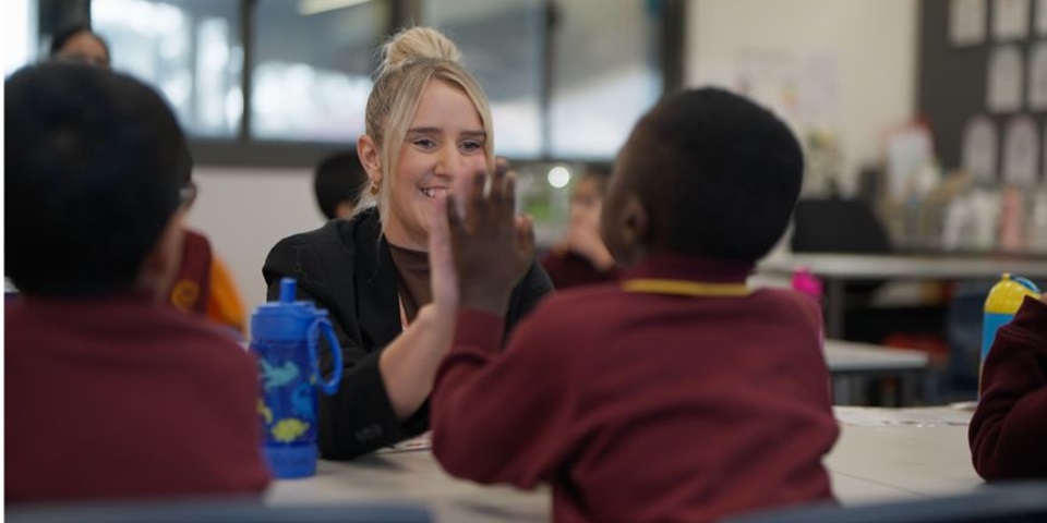 A teacher high-fiving a student, smiling.