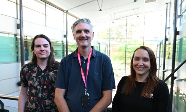 Three Murdoch academics in a glass lit room smiling