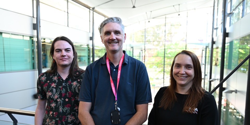 Three Murdoch academics in a glass lit room smiling