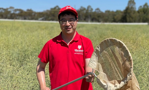 Wei Xu standing in the field with an insect catcher.