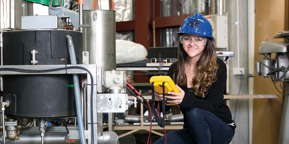 Student in hardhat next to equipment