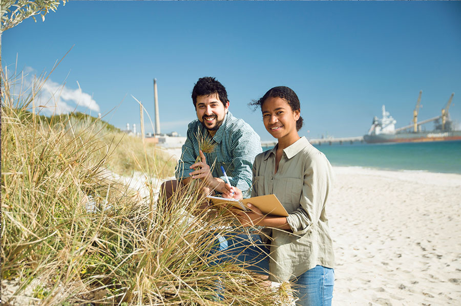 2 students on beach collecting samples