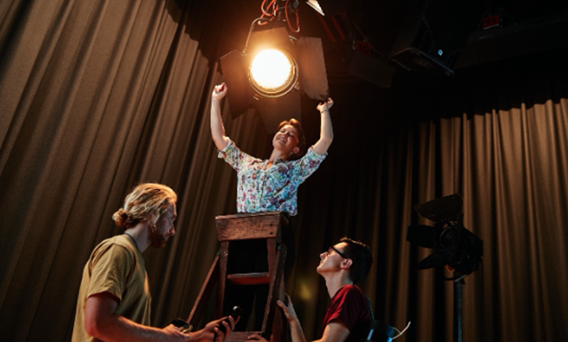 Three students setting up film studio lighting