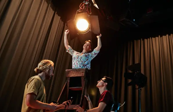Three students setting up film studio lighting