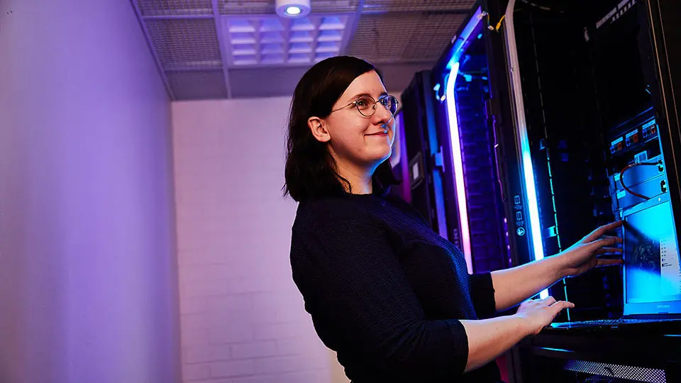 Woman smiling, computer in server room