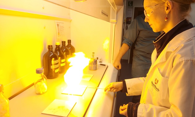 A student wearing safety goggles holds a sample of gun cotton.