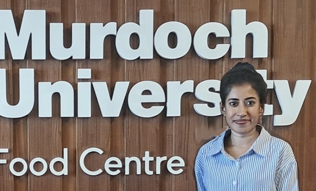 Photo of student in front of Murdoch University logo