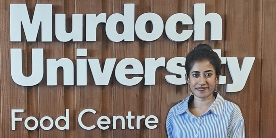 Photo of student in front of Murdoch University logo