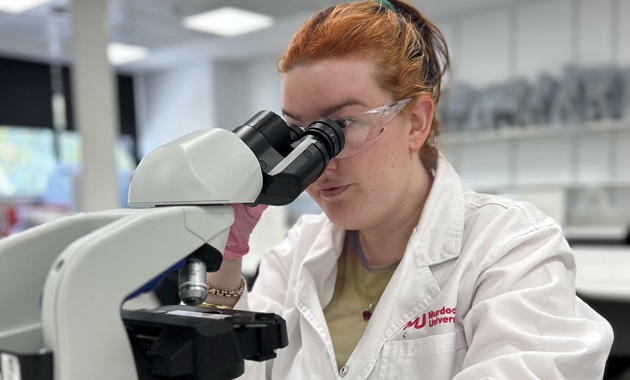 Student looking through microscope in lab