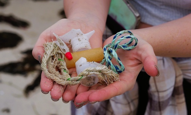 plastic free july cleanup student holding plastic waste