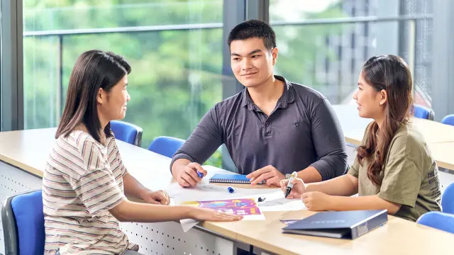 Two females and male talking over desk